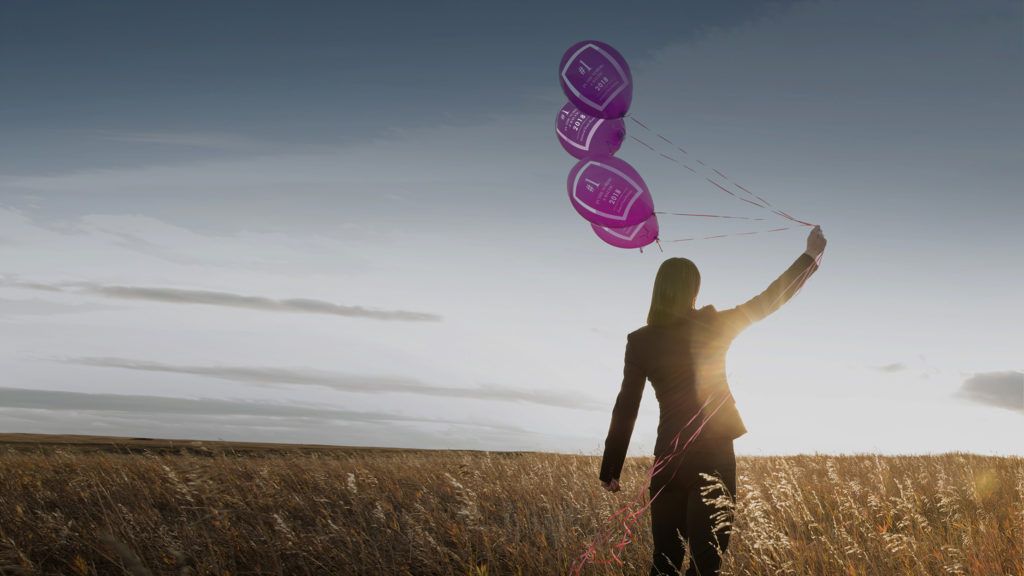 Kvinna håller i ballonger på ett fält